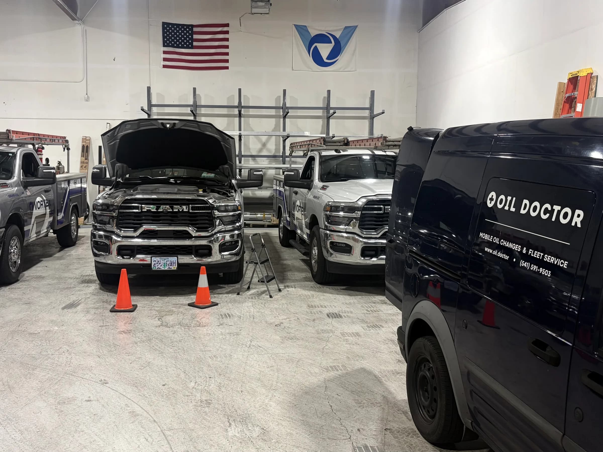 Oil Doctor van parked beside three Vortex fleet pickups, one with its hood open for service